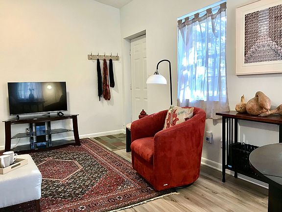 Entry door viewed across living room. Red chair now replaced with Navy blue chair.