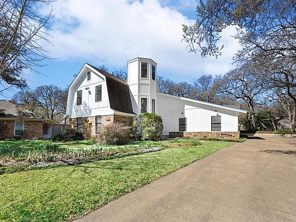 View of side of property with a gambrel roof, a lawn, and driveway