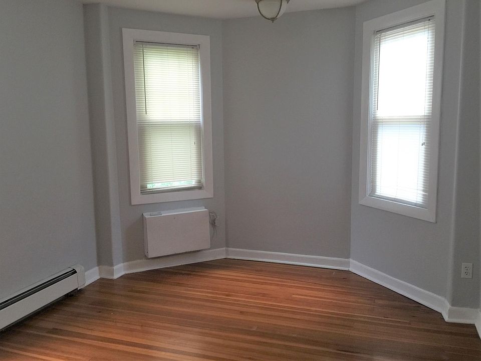 Bedroom with wall mount air conditioner with remote, hardwood floor.