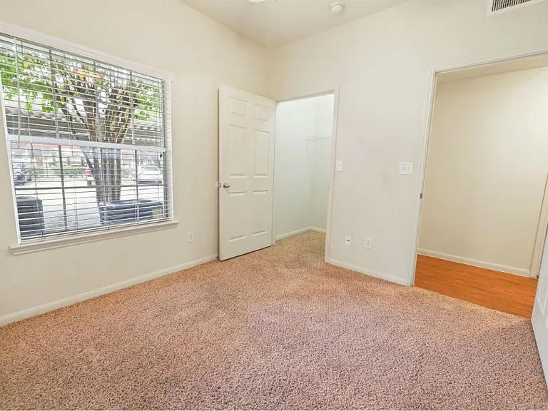 Bedroom with a large window and plush carpeting at Stonehaven Apartments in Houston, TX