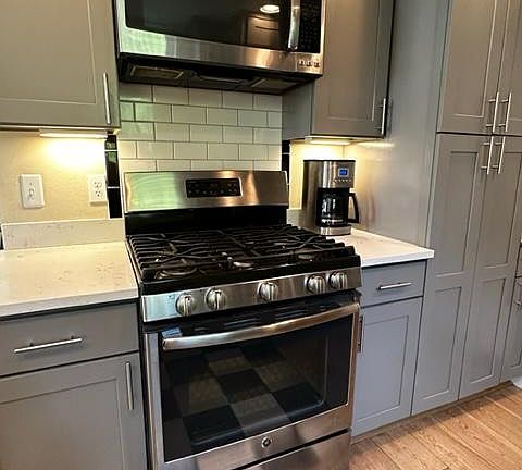Propane stove, GE Profile microwave, pantry closet, quartz countertops.