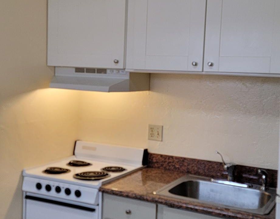 kitchen with eating counter and electric stove and refrigerator is in the corner