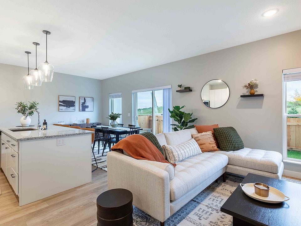 Modern living space featuring a cozy sectional sofa with elegant cushions, a sleek kitchen island with pendant lighting, and a spacious dining area opening to a scenic view.