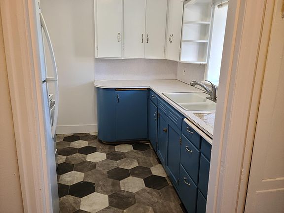 Kitchen, from laundryroom doorway. New flooring. New fridge and range. Freshly painted cabinets and walls. Built-in granite hot-mat. New faucet with pull-out sprayer.