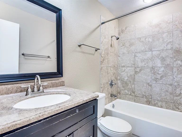 Bathroom featuring a vanity with an integrated sink, framed mirror, and a bathtub with a tiled shower surround