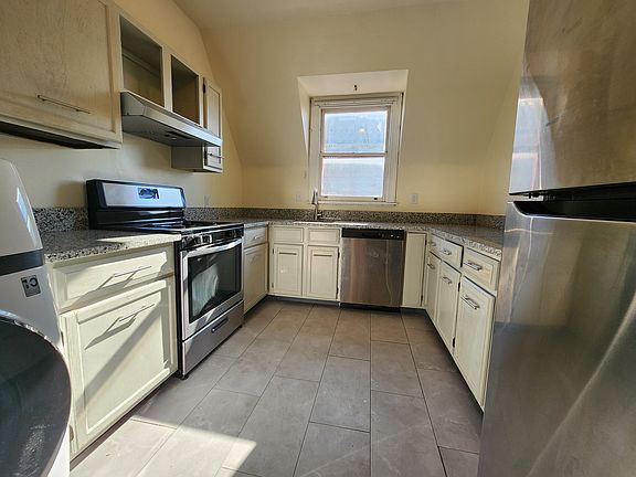 Kitchen with stainless steel dishwasher and refrigerator, granite countertops, and easy to stand on resilient flooring.