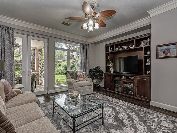 The formal living room is located across from the dining room. Spacious, light and bright with more hardwood flooring, this masterful area offers beautiful views of the back yard and pool. Notice the crown molding, ceiling fan, recent windows and the