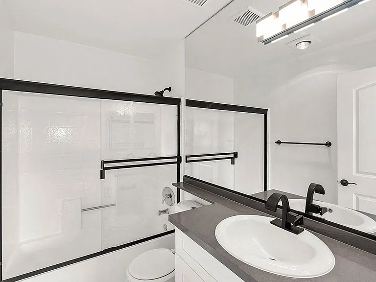 White bathroom with modern fixtures, shower, and tub.
