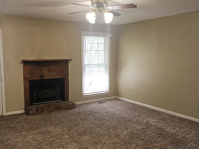 Large living room with lots of light, gas log fireplace and a door to the private patio