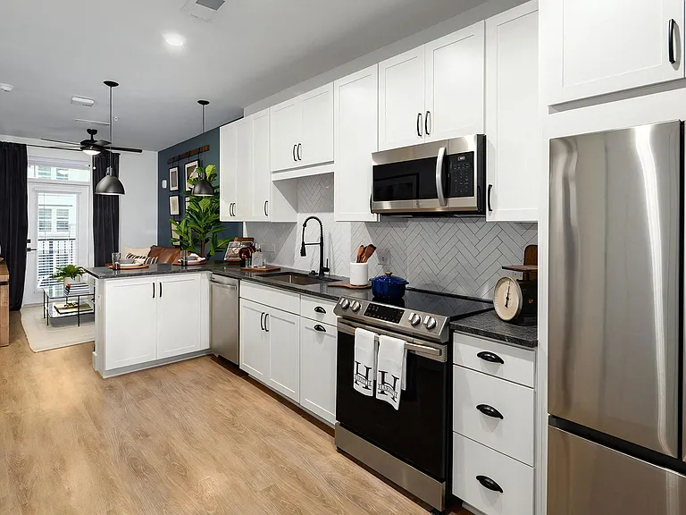 Galley-style kitchen with stainless steel appliances, white cabinets, and black countertops