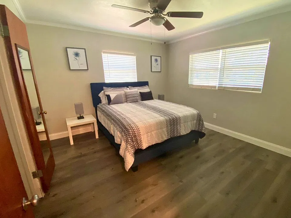 Bright queen bedroom with stylish wall art, a beautiful lamp, and elegant blinds. Lakeland, FL