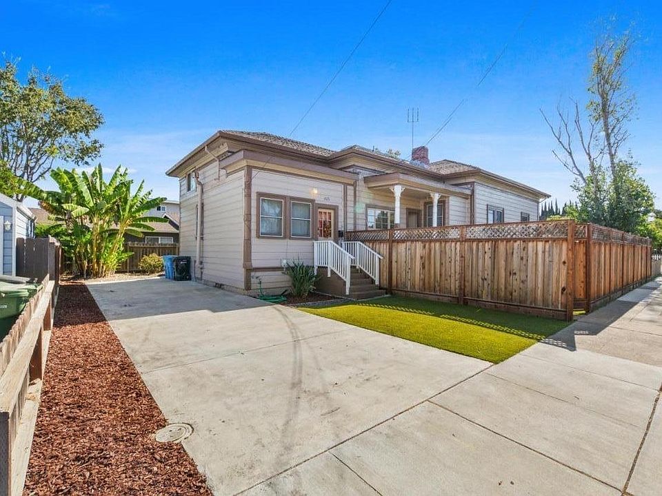 Front of house with long driveway. Front lawn has artificial turf.
