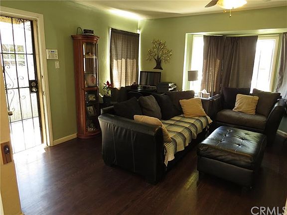Bright and airy living room with designer paint, bay window, refinished hardwood flooring, and cove ceilings