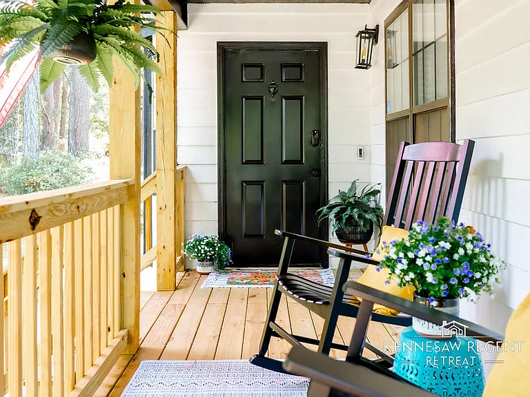 This charming covered porch offers a retreat for enjoying the outdoors. Two comfortable seats provide the perfect spot to soak up the morning sun. The porch's open design allows for easy conversation with friendly neighbors