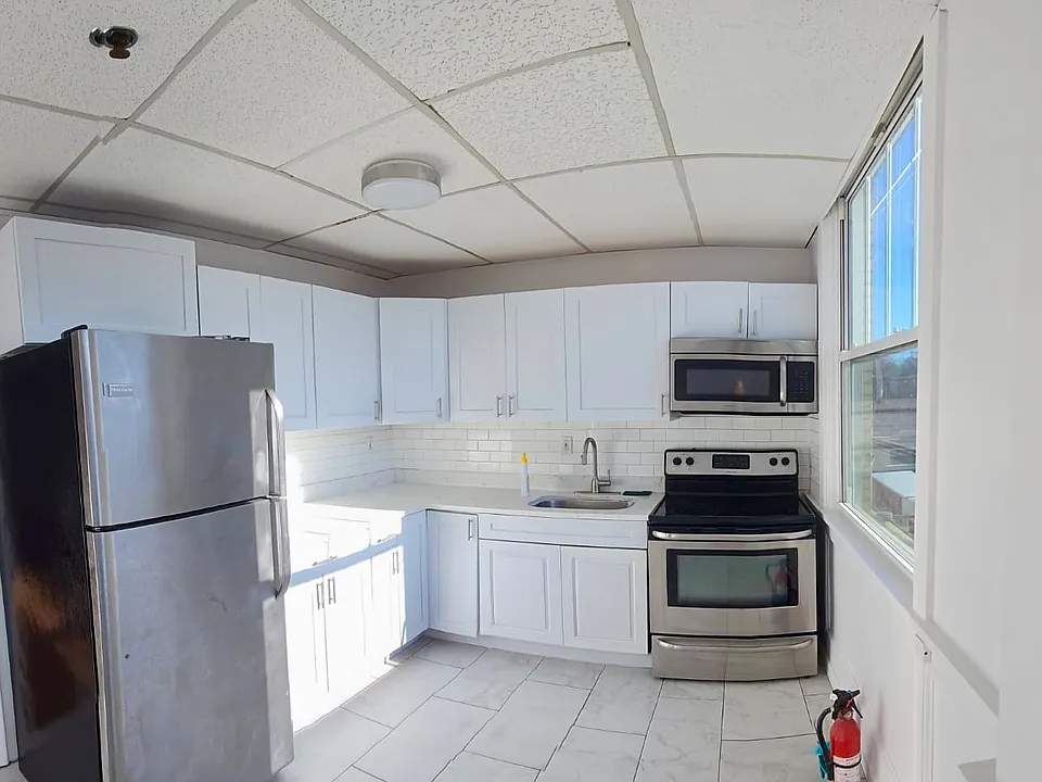 REFURBISHED KITCHEN _ Stylish black-and-white kitchen with stainless-steel appliances, tiled walls and floors, updated plumbing fixtures, and new double-pane windows.