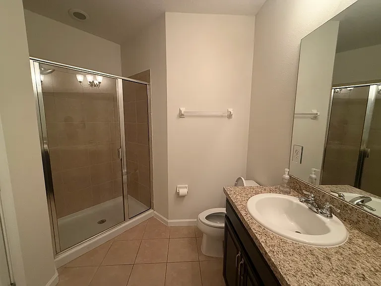 Primary bathroom with walk-in shower, granite countertops, and neutral tile.
