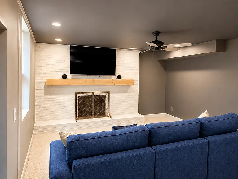 Basement office sitting area with queen size pull out couch, fireplace and large TV