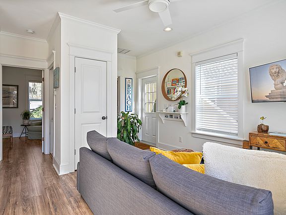 Entrance and living room with utility closet in the center. Hallway leads to stackable washer dryer then bedroom.