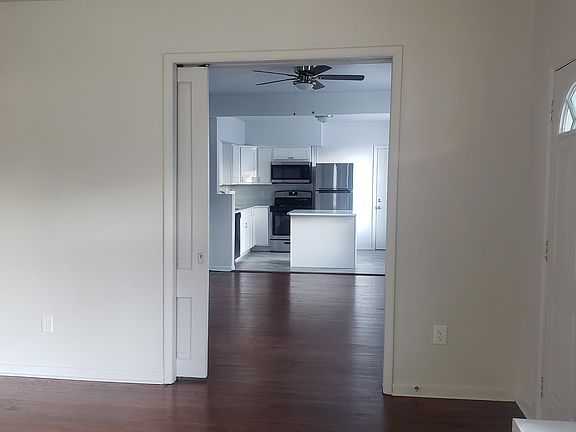 View from the living room to the kitchen. It also shows the dining/living area. The bathroom and the primary bedroom are to the left of the kitchen.