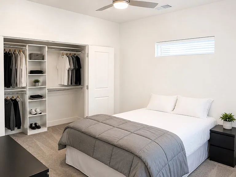 Bedroom featuring a custom-built closet system with shelving and hanging rods, a ceiling fan, and a horizontal window with blinds