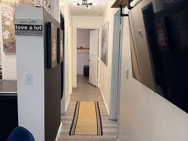Clean, updated hallway with durable plank-style flooring and overhead lighting, connecting the main rooms efficiently.