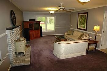 Huge living room with large windows that let in lots of natural light. Large brick fireplace and man