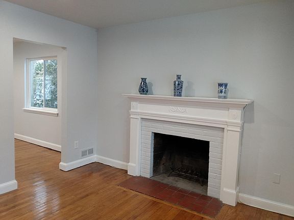 Living room with entrance to dining room on the left. Well lit with large picture window & morning sun.