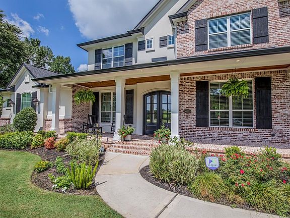 Striking Old Texas brick with white mortar & stucco compliments the black metal roof, shutters and trim. Note the details in the address plaque and sconces.