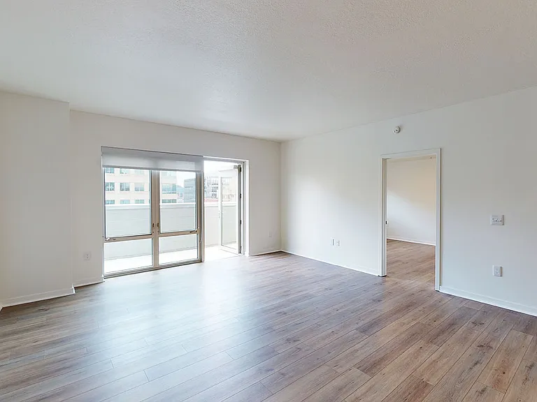 Apartment living room with wood-style flooring and patio or balcony in select homes.