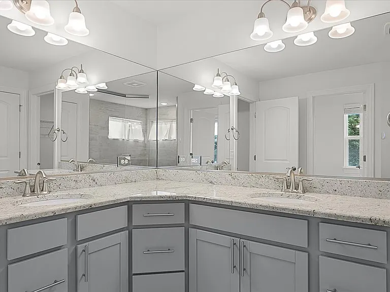 Primary bathroom with dual sinks, granite countertops, walk in shower, and walk in closet