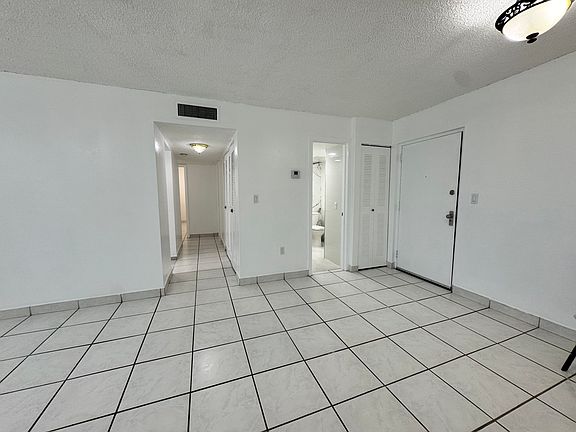 Living/dining showing entrance, 1/2 bath, and hallway to bedrooms and additional bathroom, with entrance to kitchen to the left of the hallway