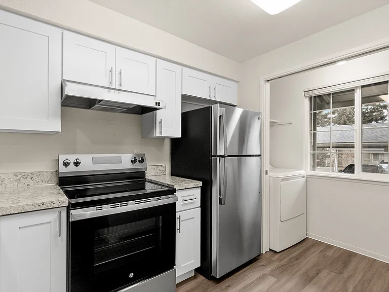 Modern kitchen with sleek stainless steel appliances, white cabinets, and large window for natural light. Modern kitchen with sleek stainless steel appliances, white cabinets, and large window for natural light.