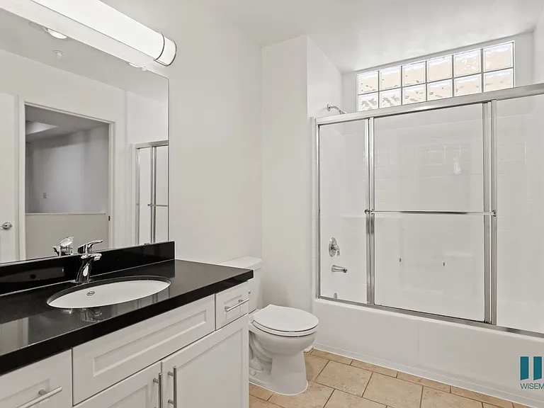 Bathroom with Full-Size Bathtub with Glass Door and Vanity Cabinet with Storage