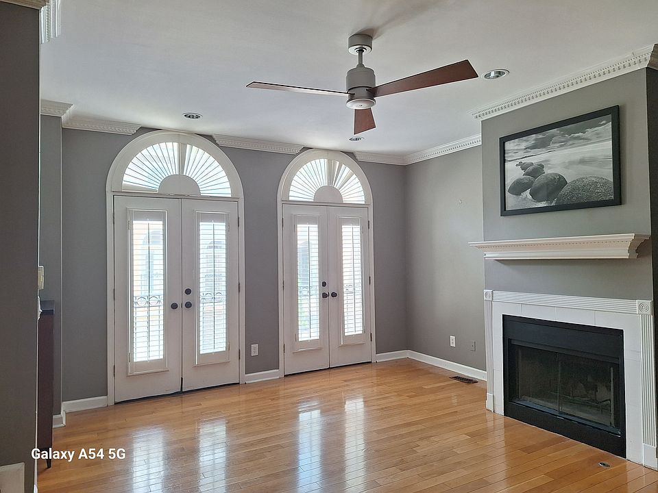 Living room with shutters, fireplace, ceiling fan, and crown molding.