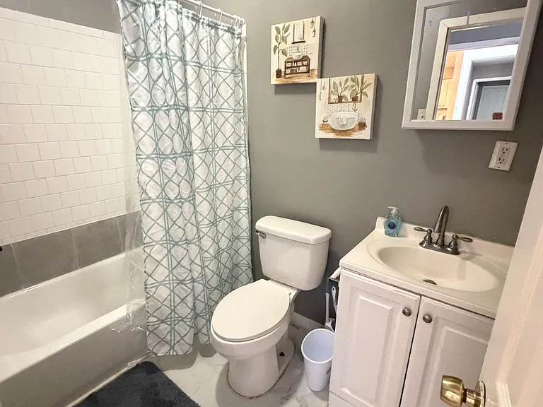 Full bathroom with tub/shower combo, tile surround, and a single-sink vanity with mirror and under-cabinet storage.