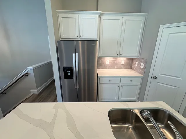 Kitchen bar with quartz countertop, refrigerator, custom cabinets with undercounter lightig