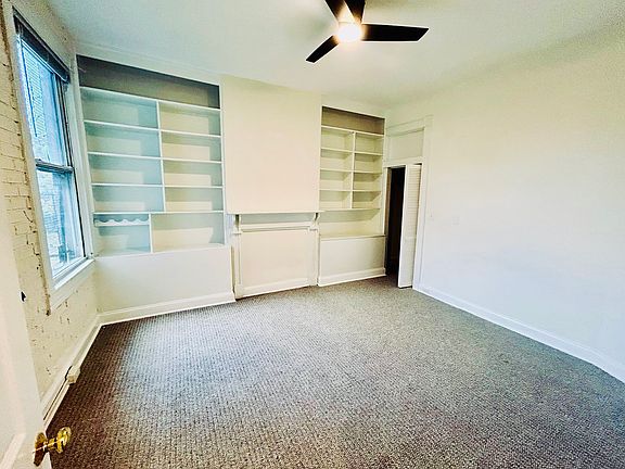 First bedroom has plenty of built-in storage, exposed brick, a large closet, and ceiling fan.
