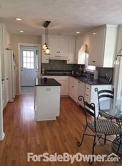 Kitchen has granite countertops, custom tile backsplash, hardwood floors.