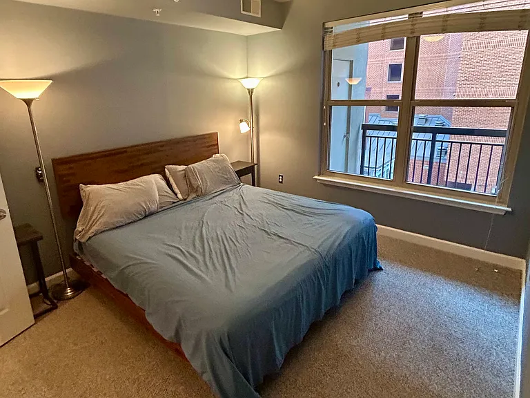 Newly carpeted and painted bedroom overlooking the private balcony featuring a king-size bed with plenty of space for an armoire or workspace.
