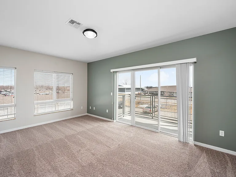 Bright and spacious living room with plush carpeting, large windows, and balcony access. Bright and spacious living room with plush carpeting, large windows, and balcony access.