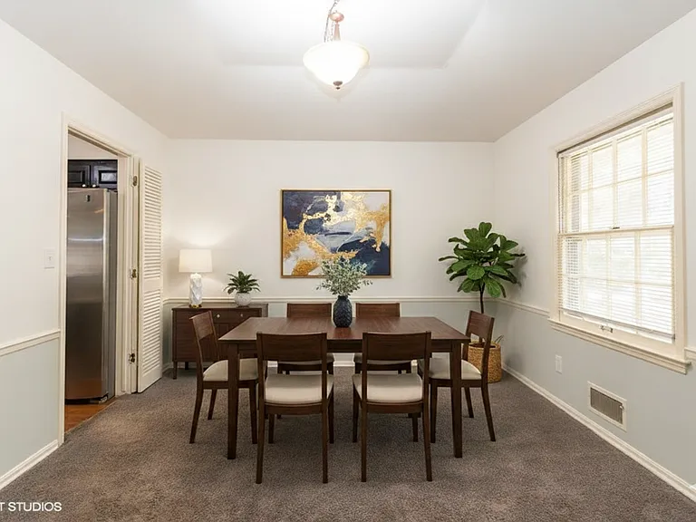 Formal dinning room off kitchen has been virtually staged. The carpet throughout the house has been replaced with dark grey luxury vinyl floors.