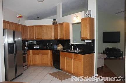 Kitchen w/ cut out & living room view
						:
						Kitchen with tile floor & stainless steel fridge opens naturally to living room