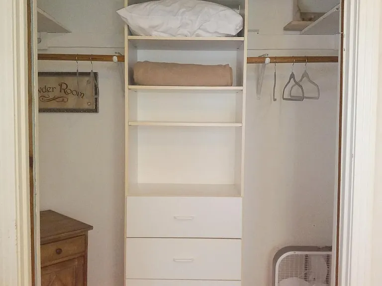 One of two bedroom storage closets with hanging and built-in drawer space, extra linens