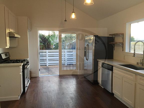 Kitchen with stove, fridge and dishwasher. Stack washer/dryer are located just passed the stove.