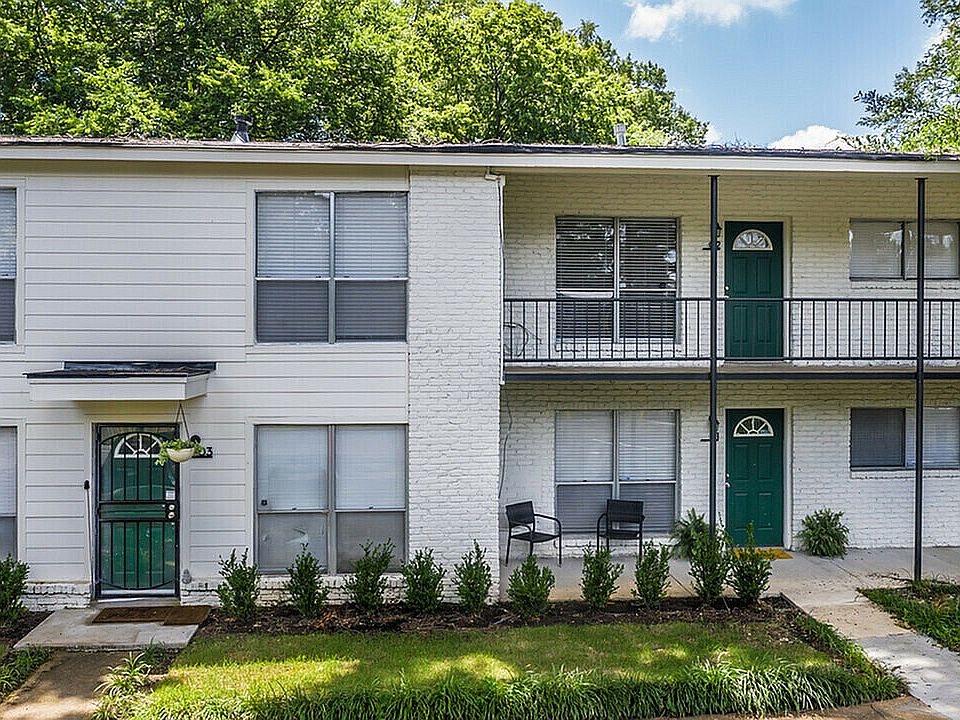Step into comfort with this serene apartment building, surrounded by lush greenery.