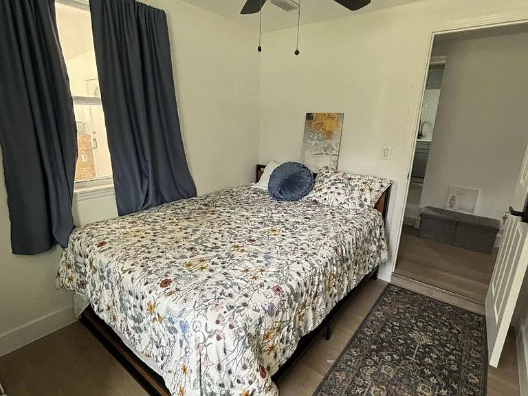 Private bedroom with a full-size bed, ceiling fan, and window with blackout curtains for added comfort and privacy.