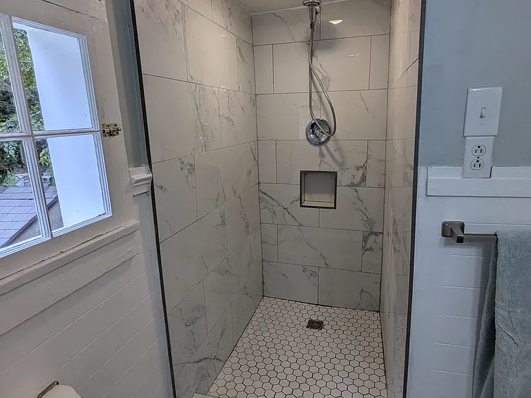 Spacious shower tiled floor to ceiling.