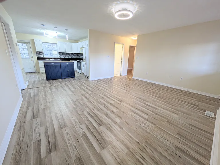 Open-Concept Entry: Step through the front door into a bright, open living space featuring brand-new laminate flooring and a direct view of the spacious kitchen