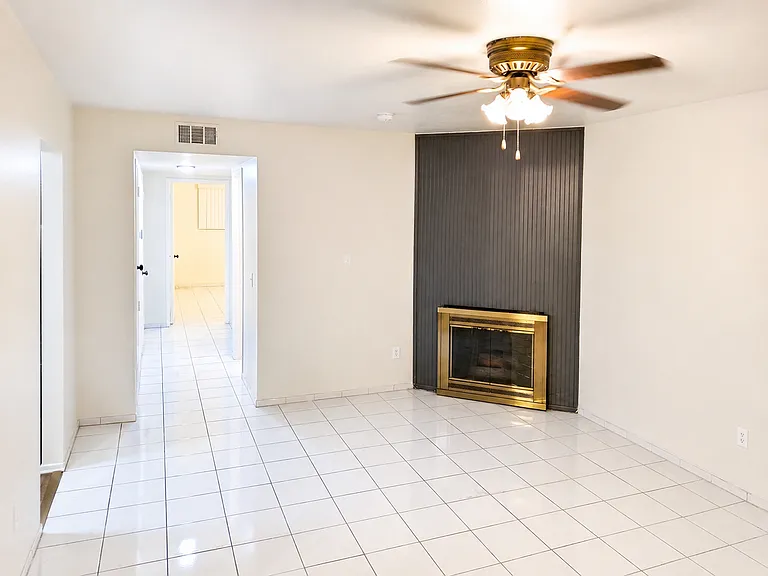 Spacious living room featuring a decorative fireplace, neutral walls, tile flooring, and a comfortable open layout.