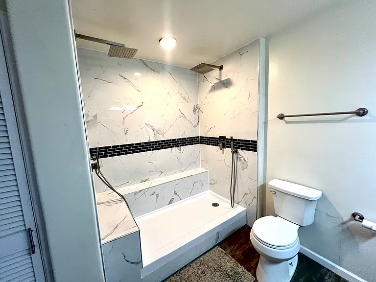 Renovated master bathroom shower with dual shower heads as well as dual handheld shower heads